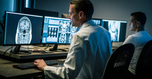Two medical professionals examining magnetic resonance imaging scans. Examination at specialized medical clinic, diagnosis and healthcare concept.