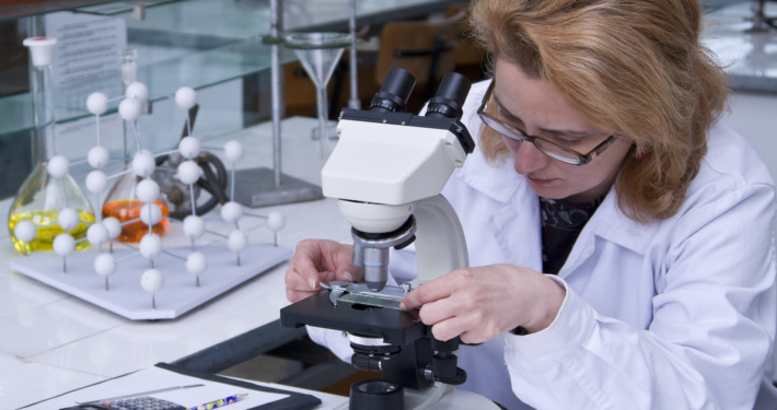 gamma knife surgery uk - Female researcher fixing a spangle on a microscope